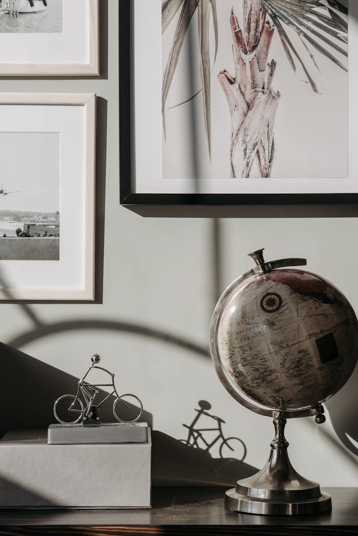team-01 A stylish indoor scene featuring a vintage globe, framed art, and a bicycle sculpture casting a shadow.